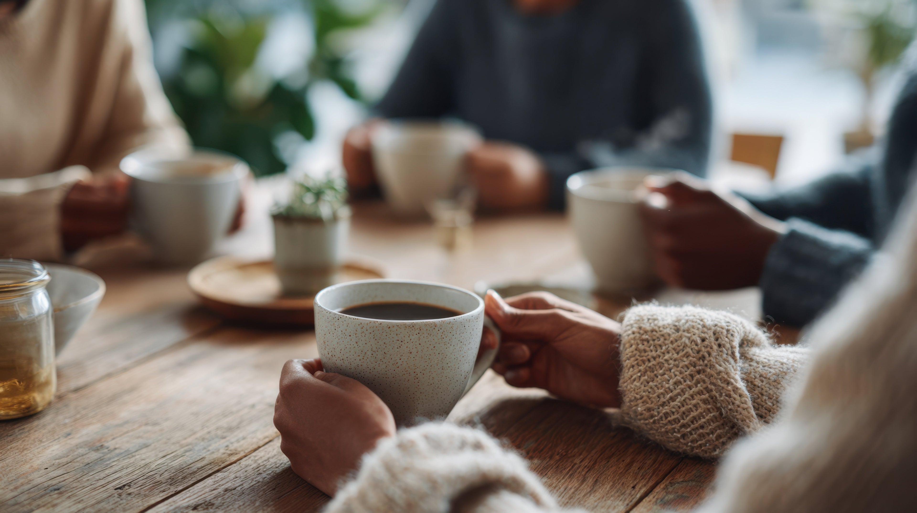 People gathered around a table enjoying EverGrace coffee together, illustrating the power of community, meaningful conversation, and connection over a shared cup of coffee.