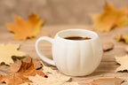 White pumpkin mug with EverGrace Coffee on a wood table with fall leaves around it.
