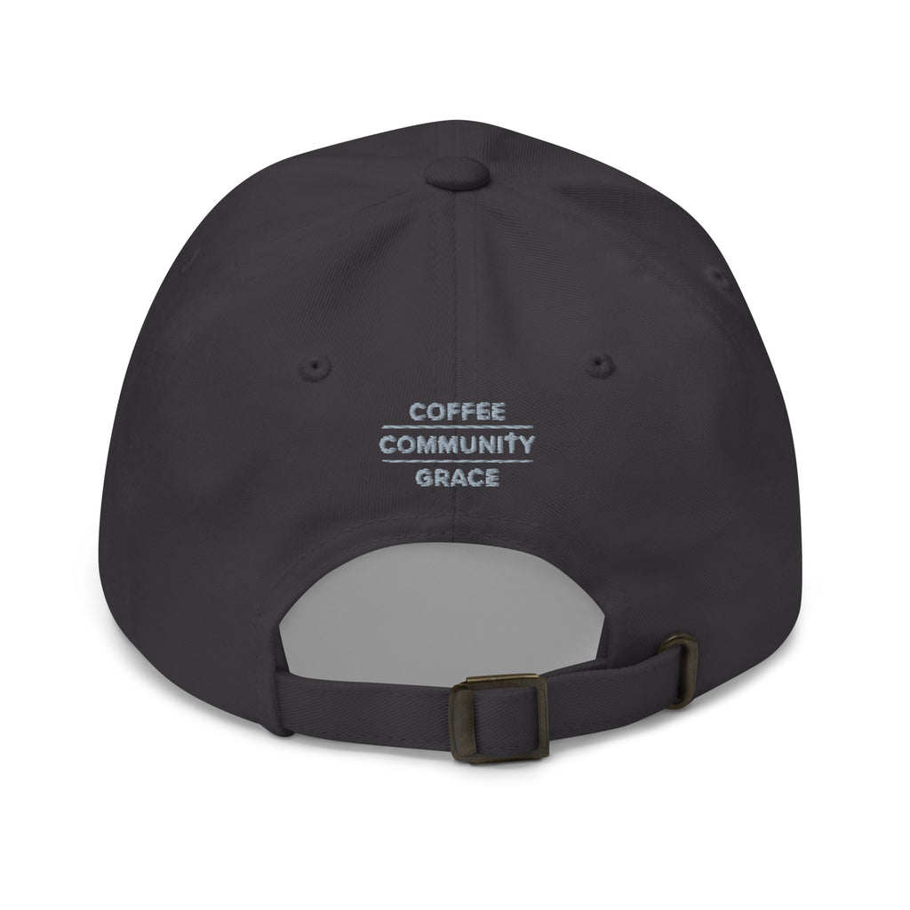 A dark charcoal gray baseball cap shown from the back, featuring the text 'COFFEE COMMUNITY GRACE' printed in white on the back panel. The cap has an adjustable dark strap with a metal buckle.